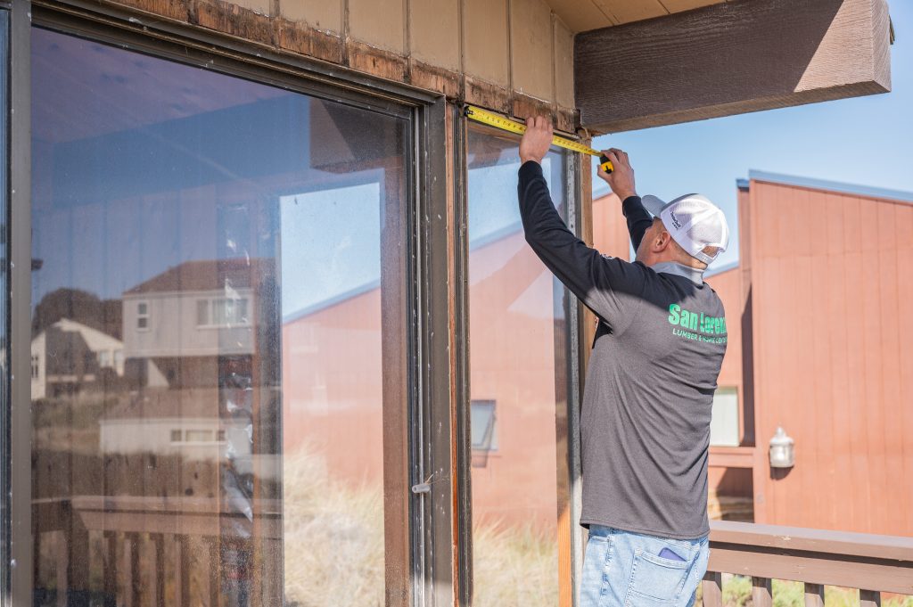 Contractor installing large window unit into exterior wall opening
