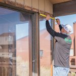 Contractor installing large window unit into exterior wall opening