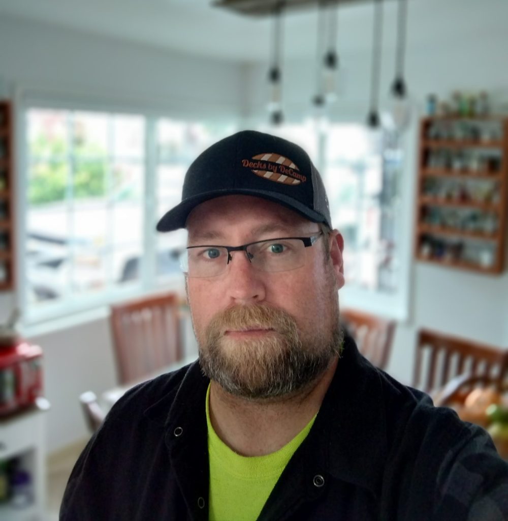 Portrait of Giles Beilby wearing glasses and baseball cap indoors