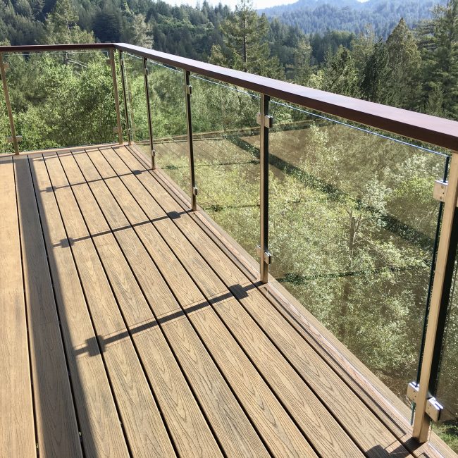 Finished residential deck with wood decking and metal railing overlooking forested landscape